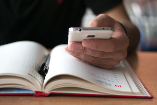 Hand holding smartphone resting on open diary